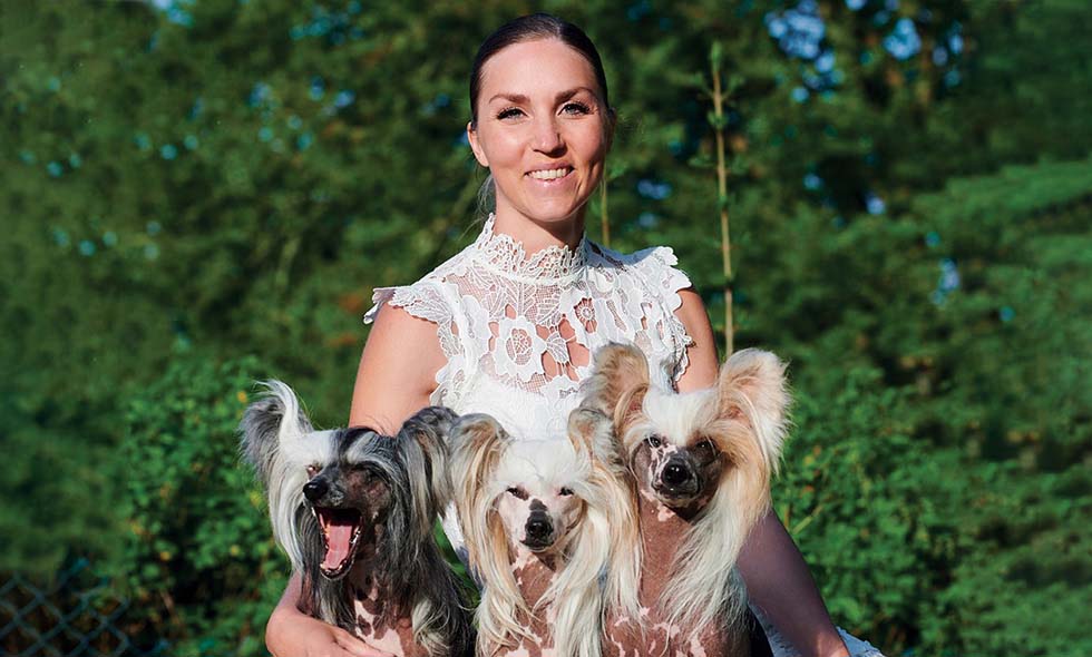 Kvinna poserar stolt med tre Chinese Crested hundar