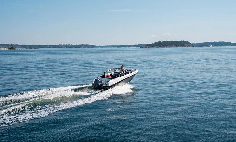 Motorbåt färdas på öppet hav med öar i bakgrunden.