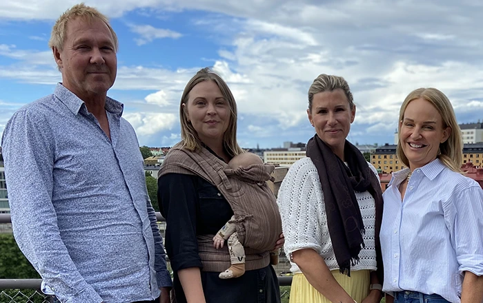 Fyra anställda på Svedea står på en takterrass med staden i bakgrunden, varav en har en bebis i sele.)