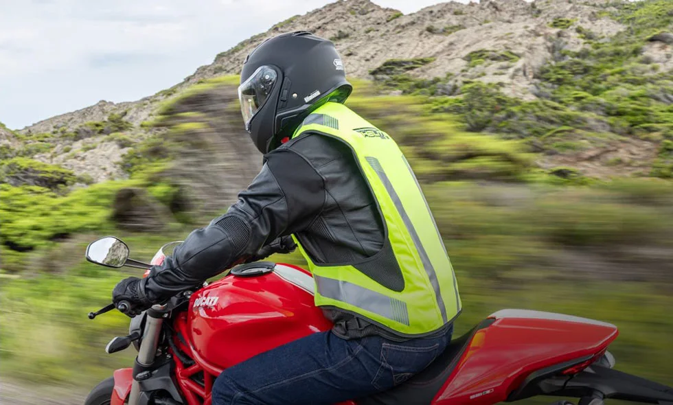 Motorcyklist i neongul väst kör på landsväg