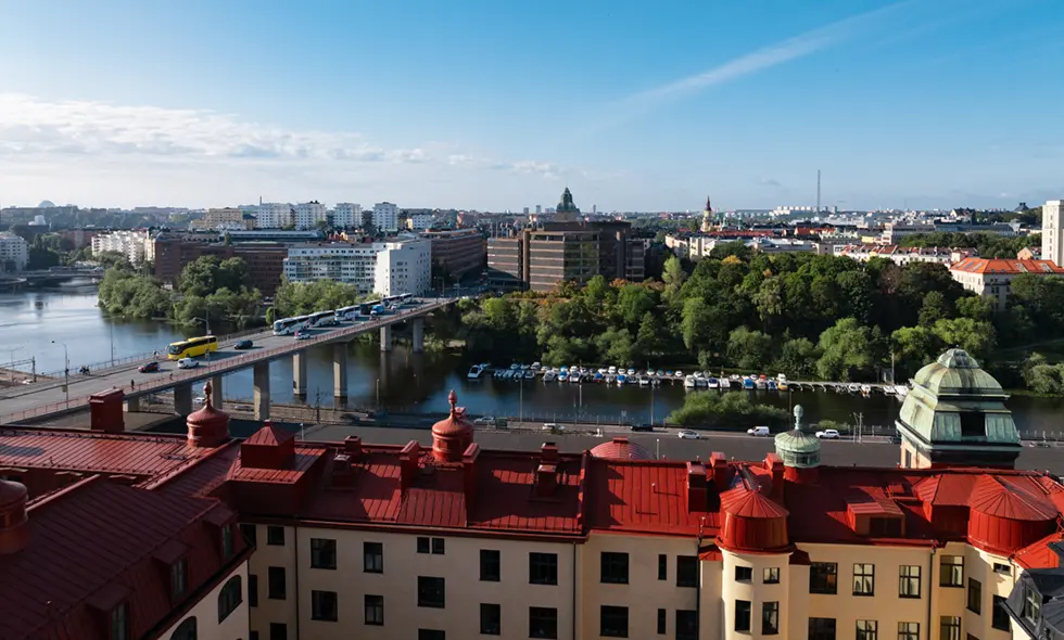 Bild tagen från högt hus med vy över tak och vatten i bakgrunden.