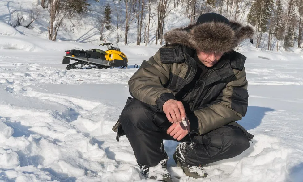 Person kontrollerar isens tjocklek vid snöskoter