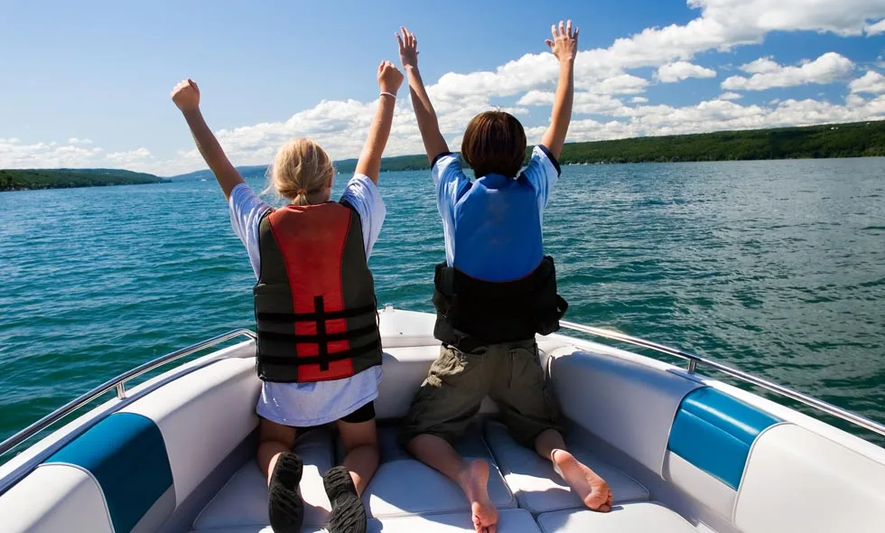 Barn på en  båt sträcker upp armarna i luften