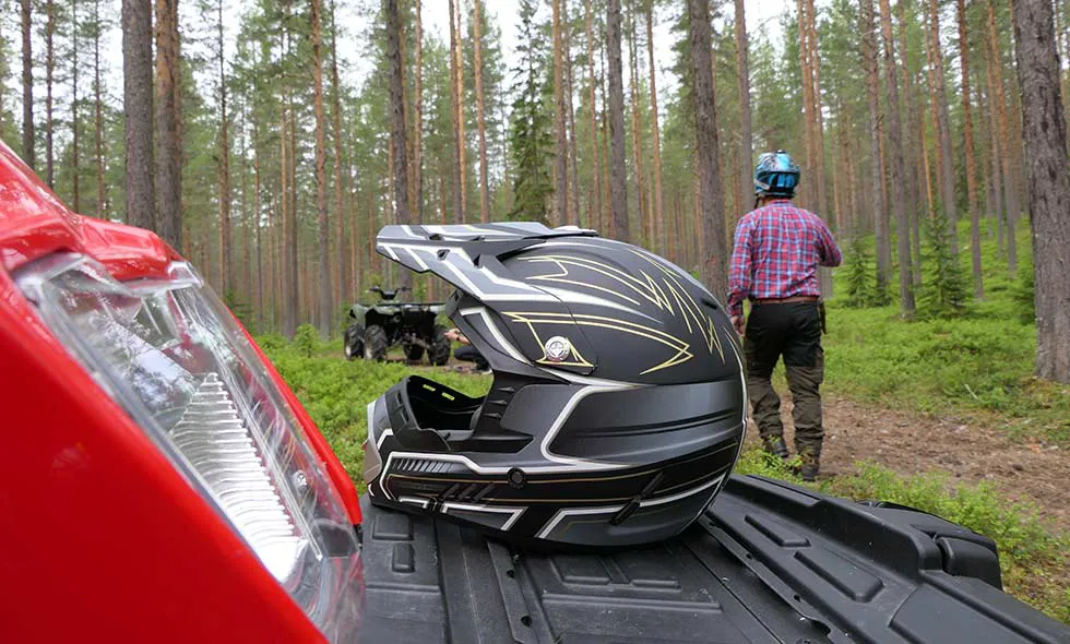 Hjälm lämplig för ATV-körning står på ATV i skogen