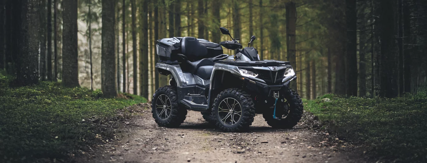 Svart ATV från CFMOTO står på skogsväg.