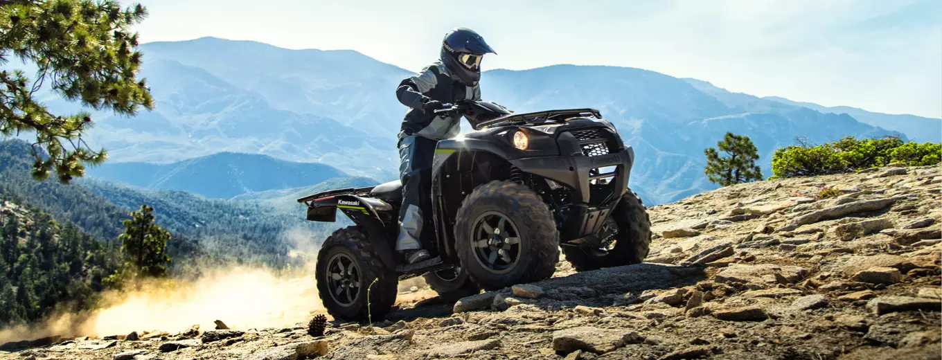 Person kör svart ATV från Kawasaki uppför stenig bergsstig.
