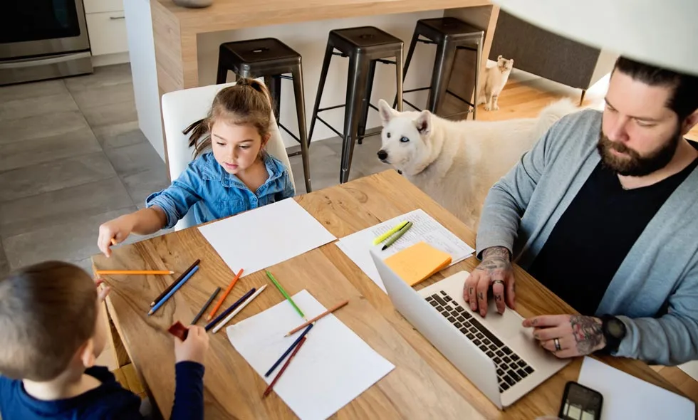 En familj på en man, en pojke, en vit hund och en liten flicka, sitter runt ett köksbord