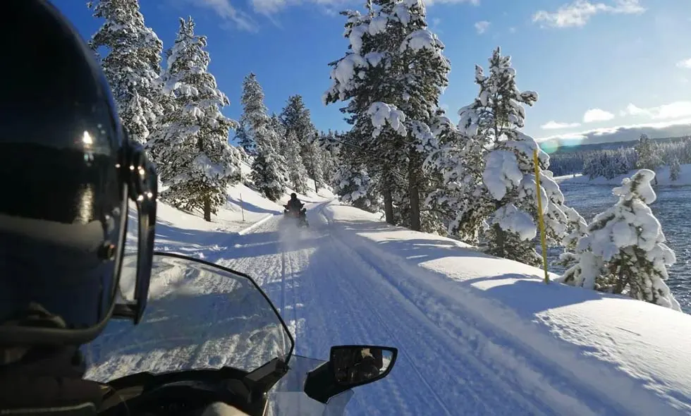 Vi sitter bakom föraren på en snöskoter och tittar framåt på skoterleden.