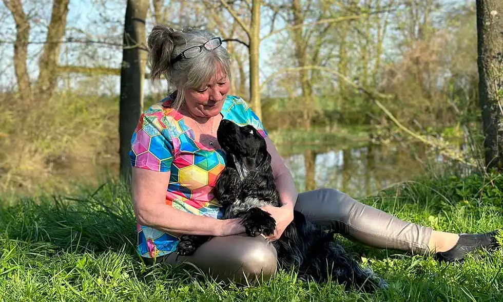 Kvinna myser med svart spaniel vid en sjö