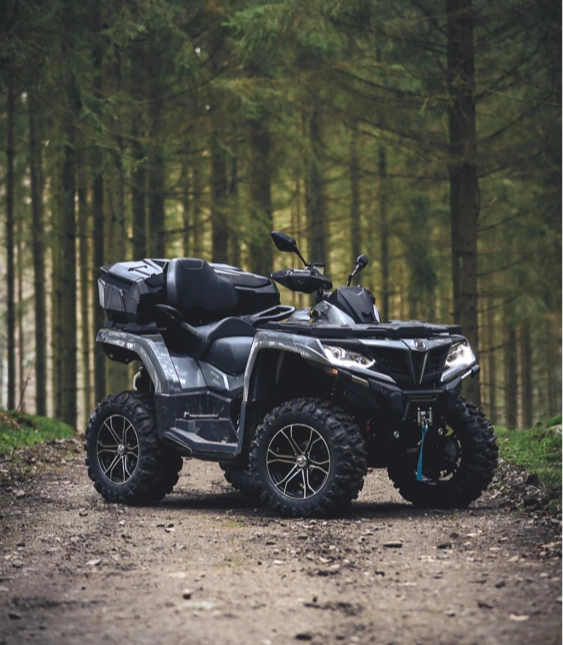 Svart ATV från CFMOTO står på skogsväg.