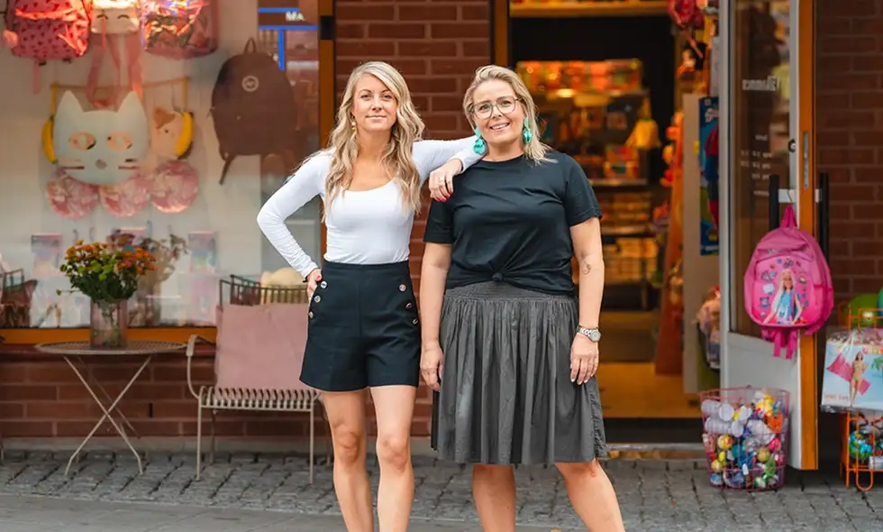 Två kvinnor står framför en butik