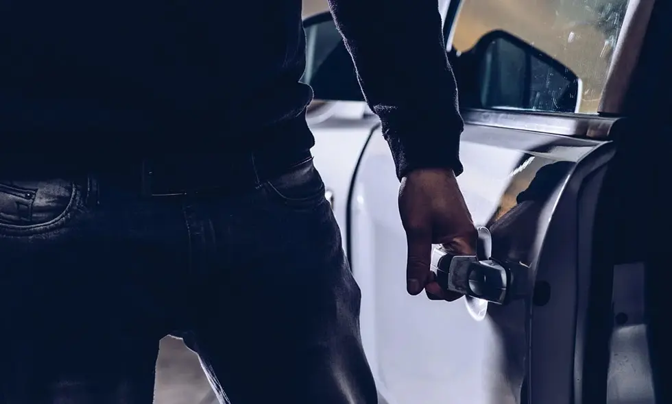 En svartklädd man håller i handtaget till en bildörr