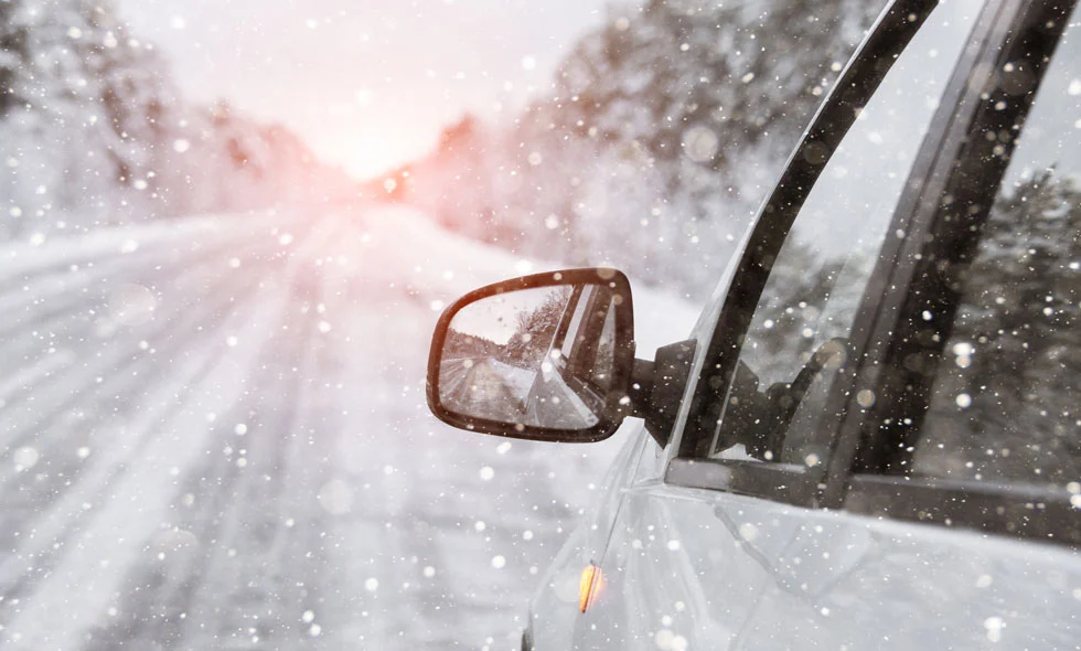 Utsnitt av en bil som kör på en snöig väg