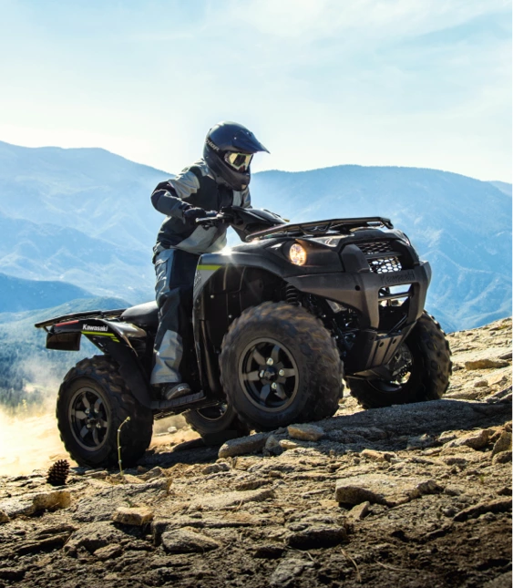 Person kör svart ATV från Kawasaki uppför stenig bergsstig.