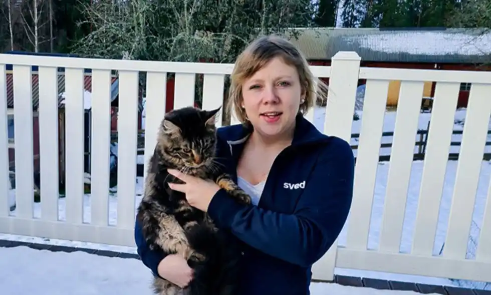Kvinna med randig katt i vinterskrud på verandan