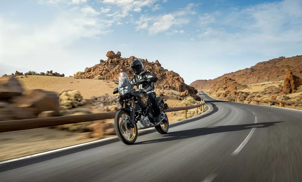 En mc från Yamaha körs längs en motorväg med berg i bakgrunden.