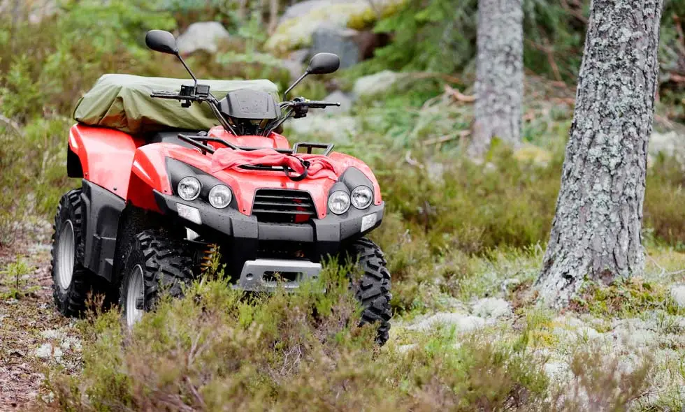 En röd ATV står i terrängen