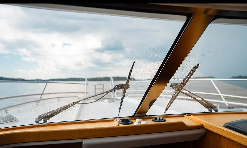 Vy från en båts förarplats med torkare på fönstret i regnoväder till sjöss.