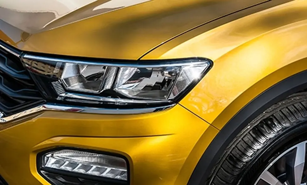 Närbild på framsidan av en gul bil med fokus på strålkastaren