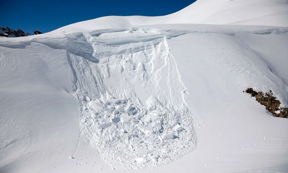 Stor snöskred i soligt bergslandskap