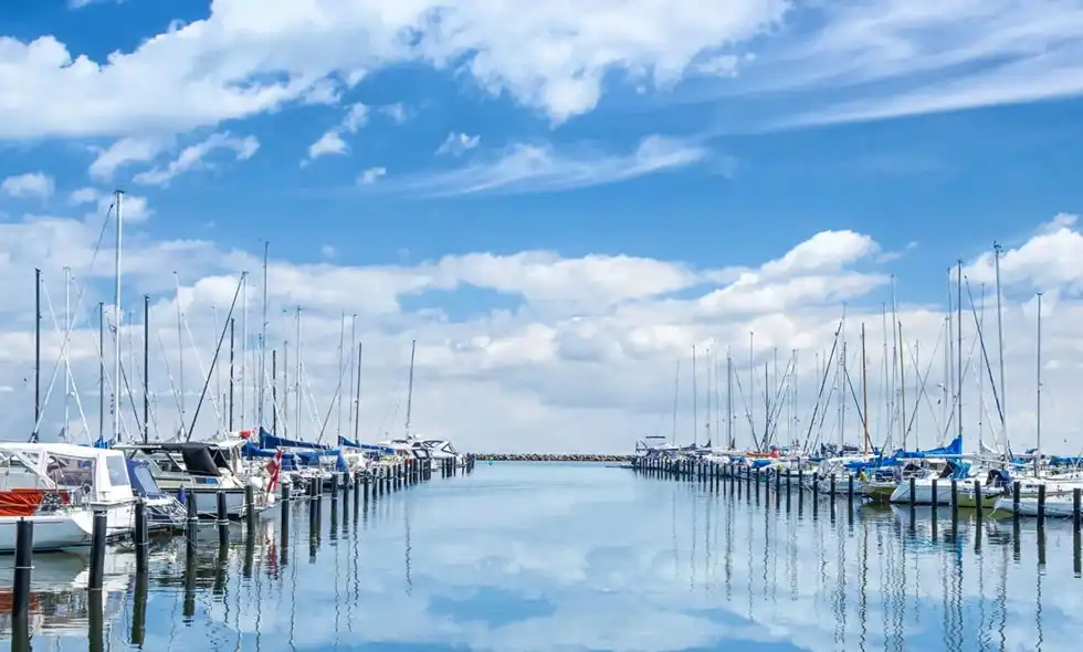 Segelbåtar i en hamn med spegelblankt vatten.