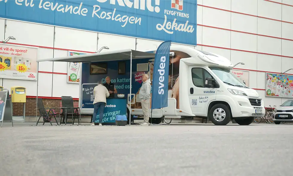 En mobil kattklinik parkerad utanför en livsmedelsaffär med texten 'Ett levande Roslagen' på byggnaden