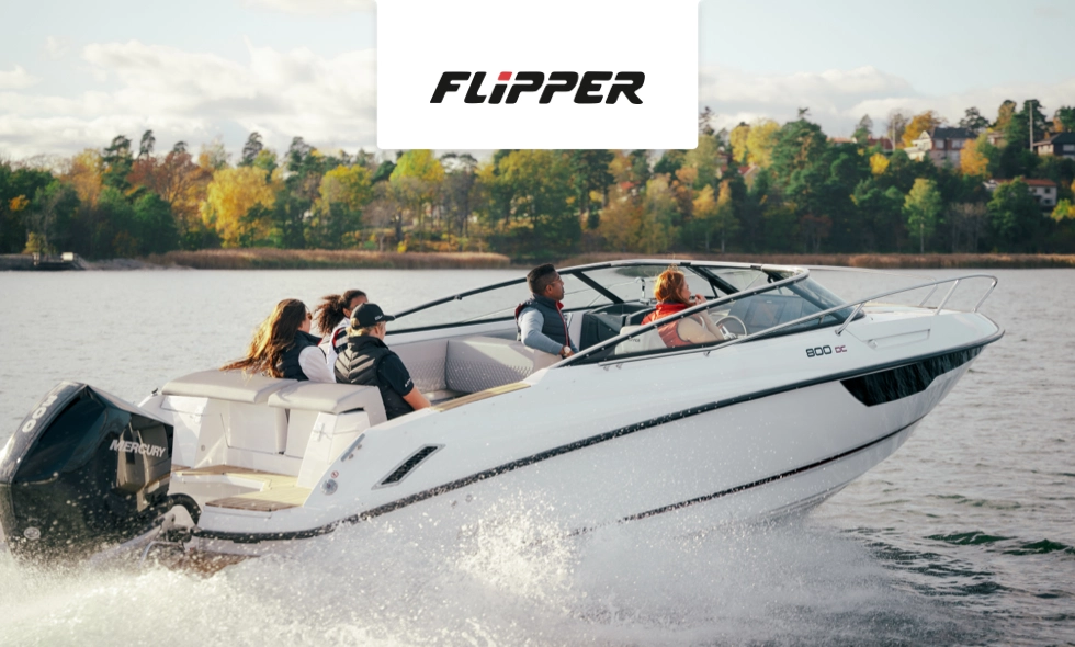 Motorbåt med fem personer färdas på en sjö, omgiven av höstfärgade träd.