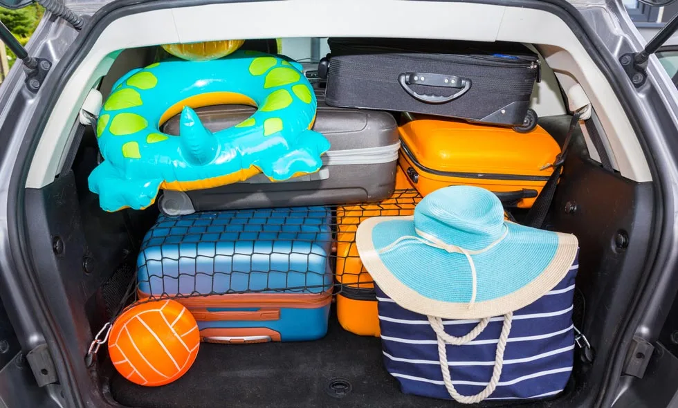 En bils baklucka fullpackad med semesterprylar inklusive badring och väskor